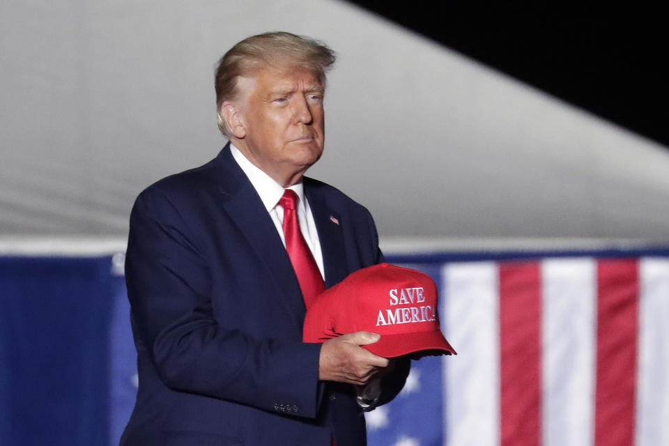 Former President Donald Trump tosses caps to the crowd as he holds a rally, Friday, Sept. 23, 2022, in Wilmington, N.C. (AP Photo/Chris Seward)