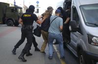 Belarusian police officers detain a man in Minsk, Belarus, Saturday, Aug. 8, 2020. On Saturday evening, police arrested at least 10 people as hundreds of opposition supporters drove through the center of the capital waving flags and brandishing clenched-fist victory signs from the vehicles' windows. The presidential election in Belarus is scheduled for August 9, 2020. (AP Photo/Sergei Grits)