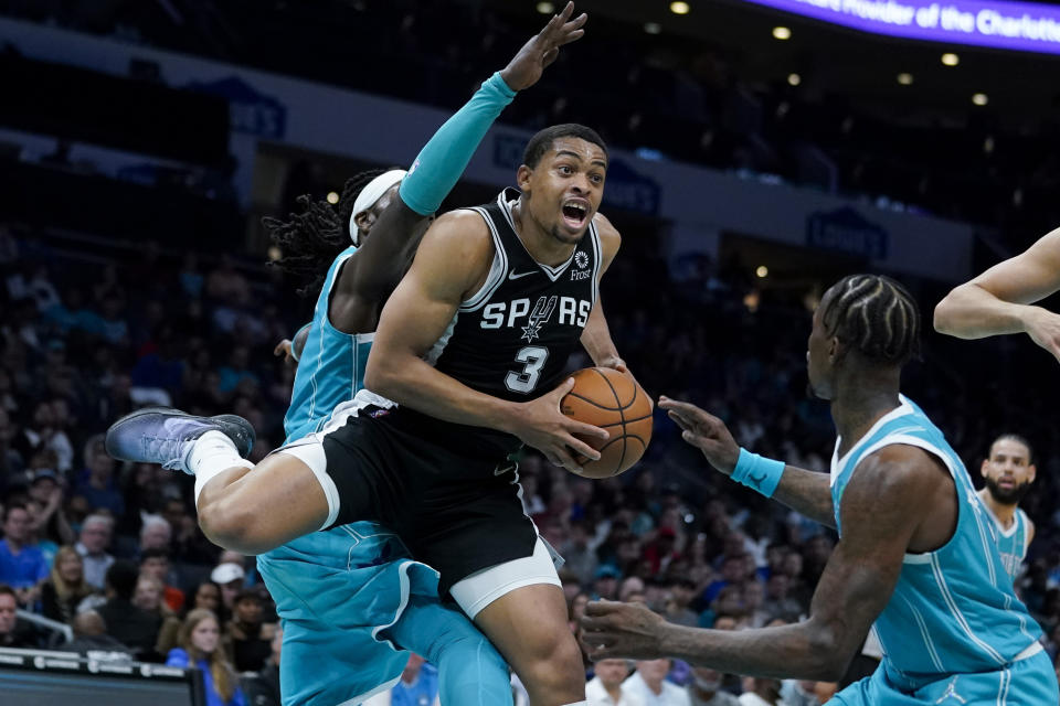 San Antonio Spurs forward Keldon Johnson drives to the basket between Charlotte Hornets center Montrezl Harrell and guard Terry Rozier during the second half of an NBA basketball game on Saturday, March 5, 2022, in Charlotte, N.C. (AP Photo/Chris Carlson)