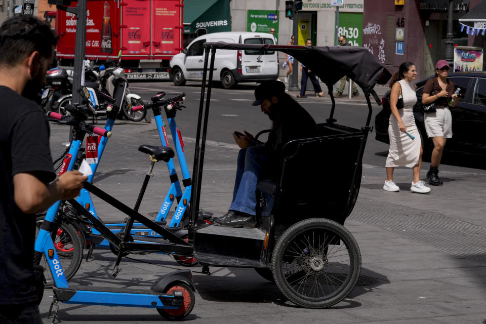 A tourist peddle-taxi driver waits in the shade for customers in Madrid, Spain, Tuesday, July 18, 2023. Temperatures are expected to peak today in some Mediterranean countries, with thermometers possibly hitting about 46 Celsius (114.8) in some parts of Spain (AP Photo/Paul White)