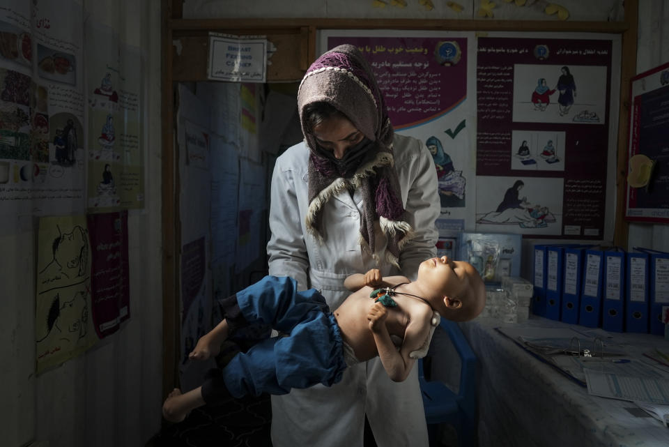 A nurse checks the weight of a child in a makeshift clinic organized by World Vision at a settlement near Herat, Afghanistan, Dec. 16, 2021. Malnutrition stalks the most vulnerable, and aid groups say more than half the population faces acute food shortages. (AP Photo/Mstyslav Chernov)