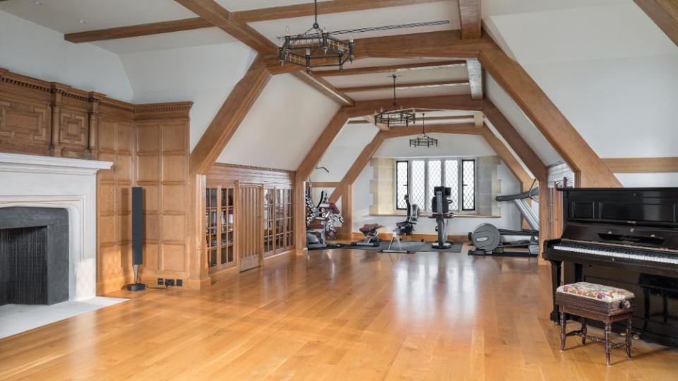 The eaves rom, which features the gym, a piano, and a fireplace. - Credit: Douglas Elliman Realty/Knight Frank