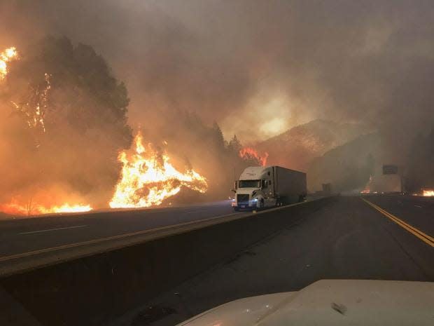 A big rig on Interstate 5 passes on Wednesday, Sept. 5, 2018 a wall of flames from the Delta Fire.