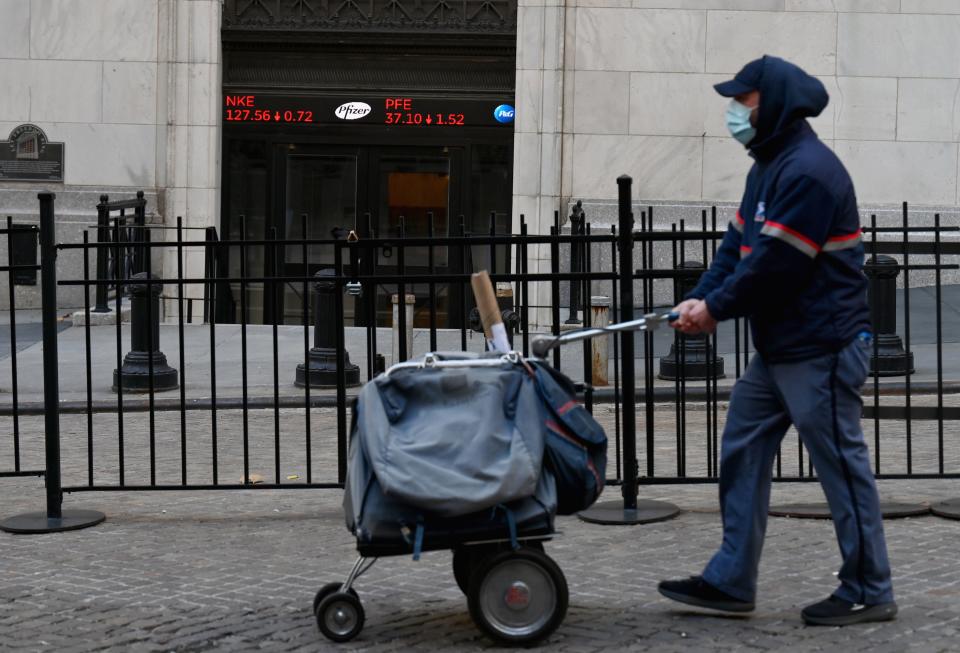 A USPS mail carrier walks past the New York Stock Exchange (NYSE) at Wall Street on November 16, 2020 in New York City. - Wall Street stocks rose early following upbeat news on a coronavirus vaccine and merger announcements in the banking and retail industries. (Photo by Angela Weiss / AFP) (Photo by ANGELA WEISS/AFP via Getty Images)