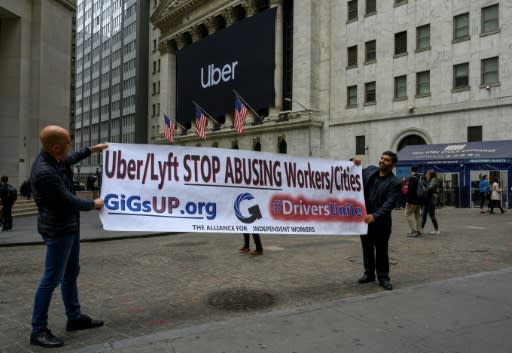Drivers hold up a protest sign in front of the New York Stock Exchange to express displeasure over ride-hailing working conditions as Uber made its market debut