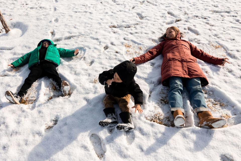 Lauren Hess and her children make snow angels at the park by their home in Syracuse on Saturday, Jan. 6, 2024. Hess has worked to make her home cozy and to appreciate unique aspects of the season in an effort to boost her mood during the winter. | Megan Nielsen, Deseret News