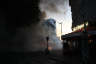 A restaurant and a burning barricade are pictured during a demonstration Tuesday, June 2, 2020 in Paris. Paris riot officers fired tear gas as scattered protesters threw projectiles and set fires at an unauthorized demonstration against police violence and racial injustice. Several thousand people rallied peacefully for two hours around the main Paris courthouse in homage to George Floyd and to Adama Traore, a French black man who died in police custody. (AP Photo/Michel Euler)