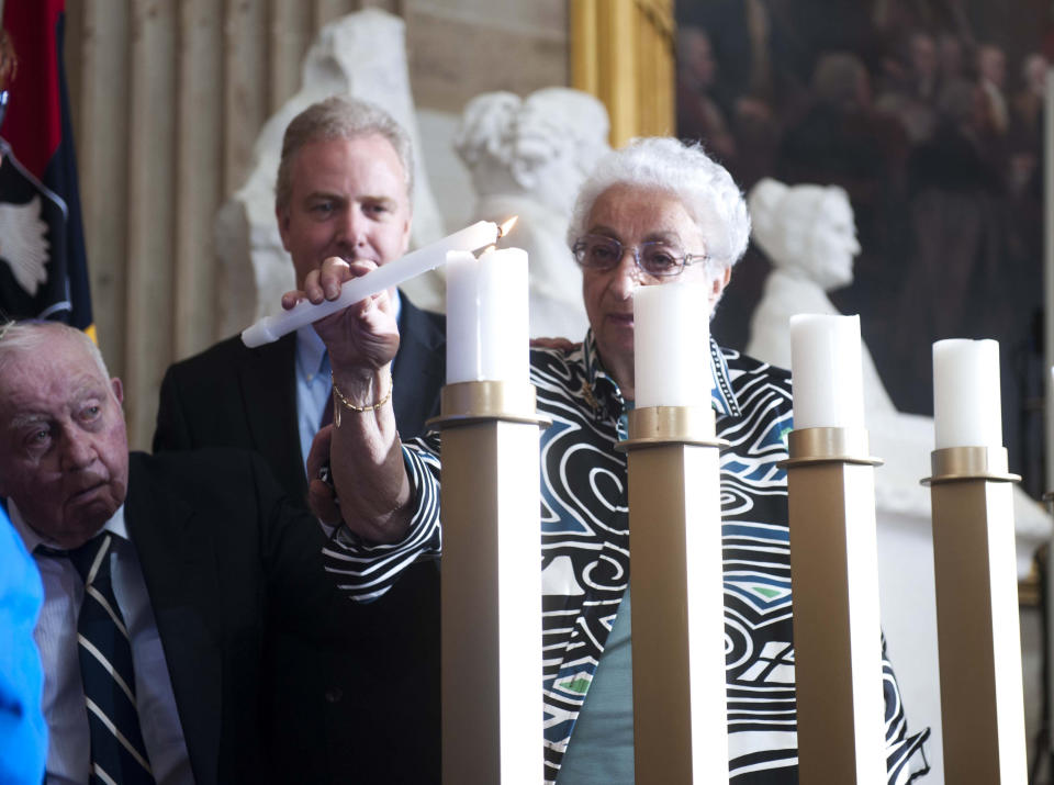 Rep. Chris Van Hollen, D-Md., center, and Holocaust survivors Inge Berg Katzenstein, right, and her husband, Werner Katzenstein, left, light a memorial candle during a Days of Remembrance ceremony in the Capitol Rotunda on Capitol Hill in Washington, Thursday, April 11, 2013. (AP Photo/Kevin Wolf)