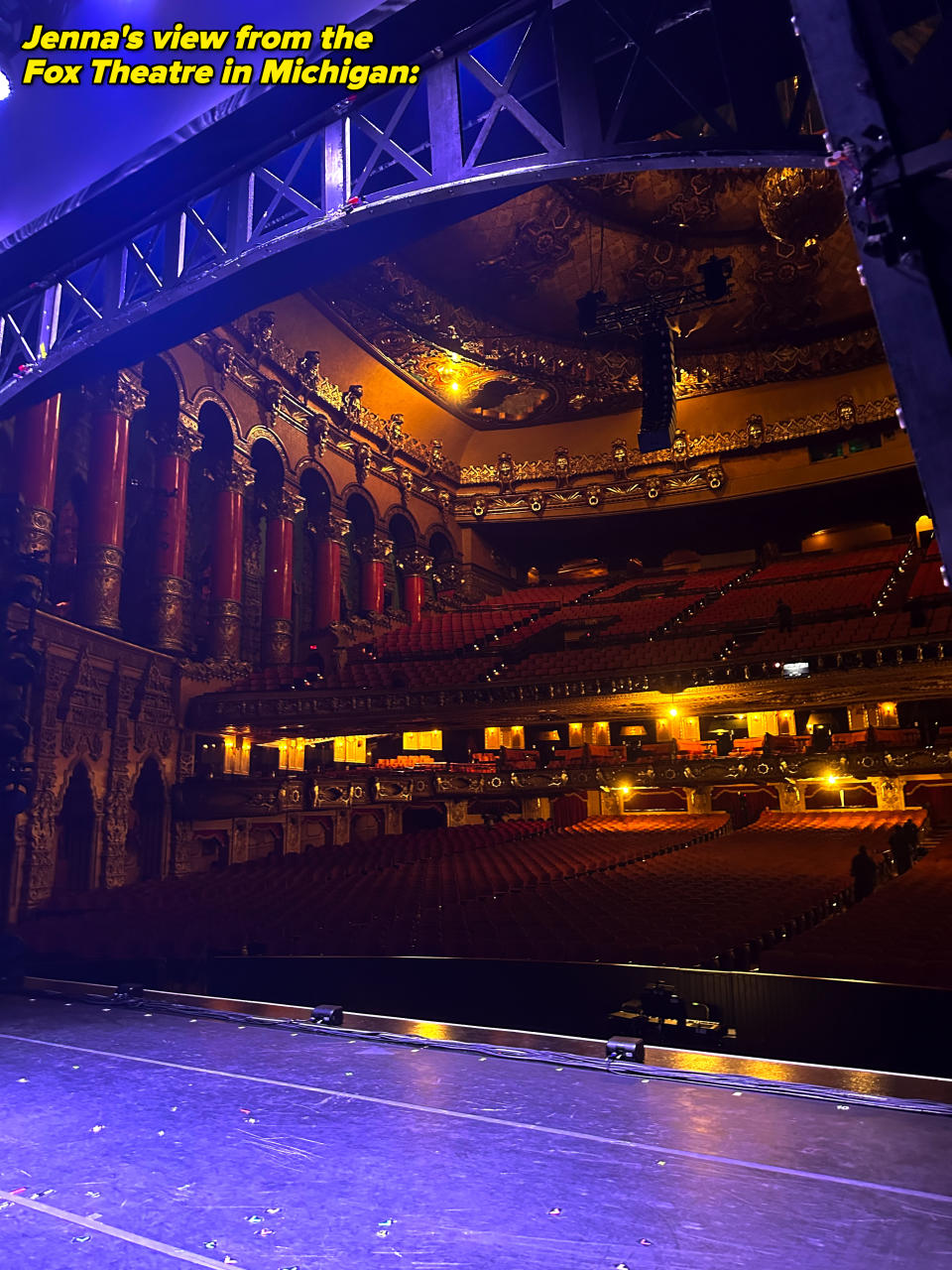 An empty, ornate theater with red seats and golden decorations, viewed from the stage, indicating grandeur and readiness for an upcoming performance or event