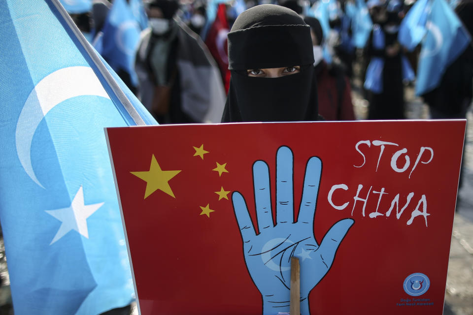 A protester from the Uyghur community living in Turkey holds up an anti-China placard during a protest against the visit of China's Foreign Minister Wang Yi to Turkey, in Istanbul, Thursday, March 25, 2021. Hundreds protested against the Chinese official visit and what they allege is oppression by the Chinese government to Muslim Uyghurs in the far-western Xinjiang province. (AP Photo/Emrah Gurel)