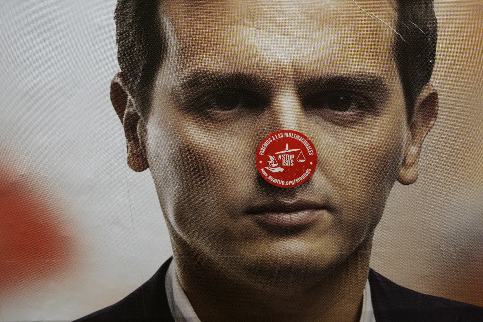 A sticker reading in Spanish "Stop multinationals" is seen on a banner of Spanish election runner Citizens party's Albert Rivera in a subway station Madrid, Spain, Friday, April 26, 2019. Appealing to Spain's large pool of undecided voters, top candidates on both the right and left are urging Spaniards to choose wisely and keep the far-right at bay in Sunday's general election. (AP Photo/Andrea Comas)