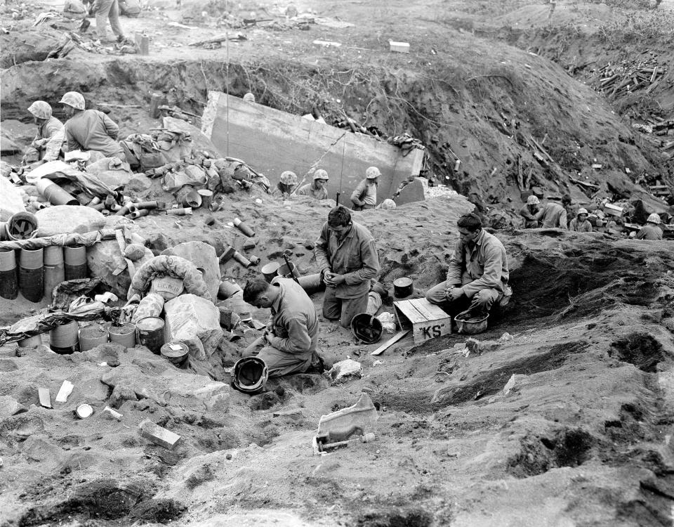 U.S. Marines kneel in prayer before they receive communion during a pause in the fighting for Motoyam Airstrip No. 1 on Iwo Jima on March 1, 1945.