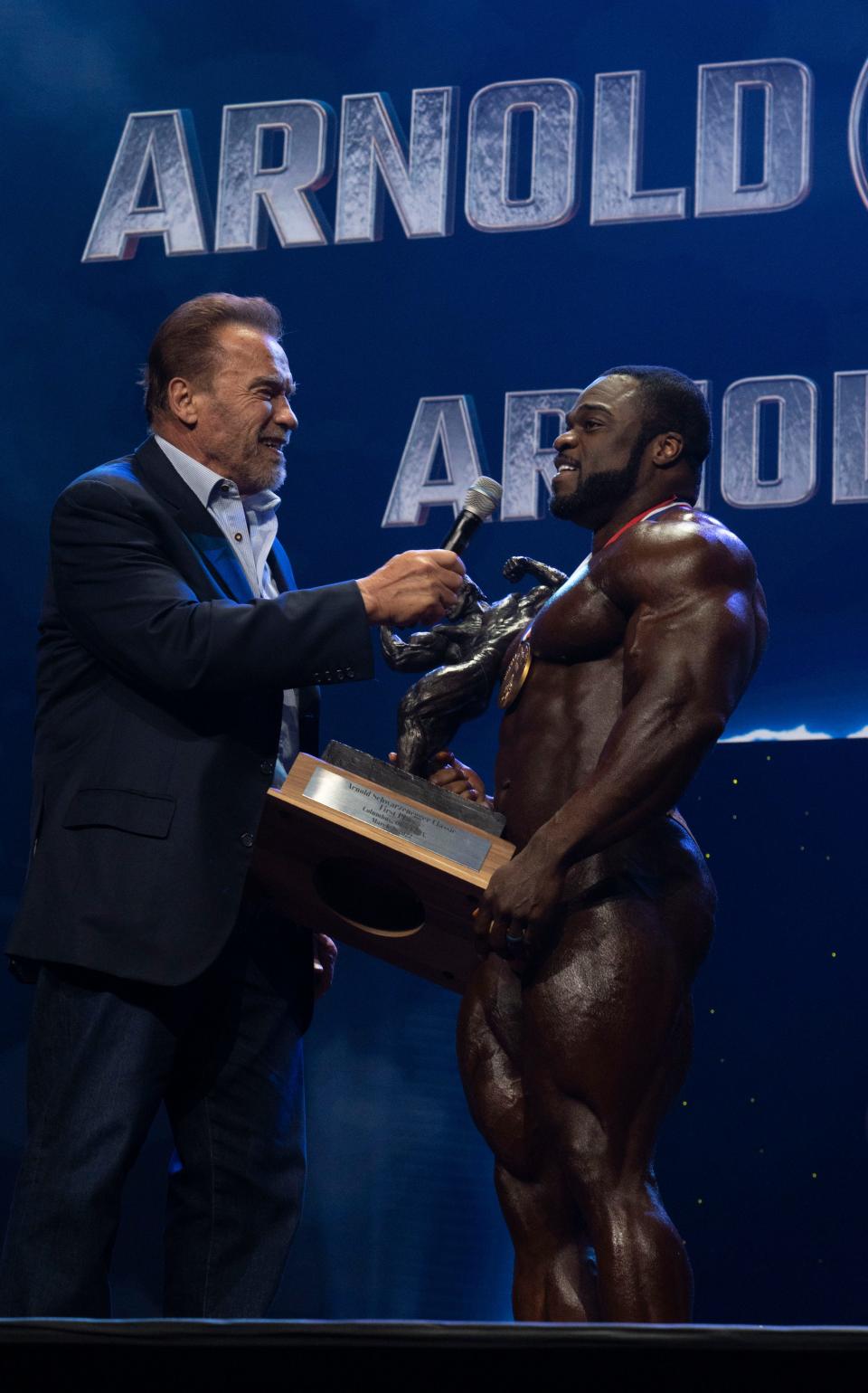 Arnold Schwarzenegger presents the first place trophy to Brandon Curry for the Pro Bodybuilding Arnold Classic during the Arnold Classic Finals at the Greater Columbus Convention Center in Columbus, Ohio, on Saturday, March 5, 2022.