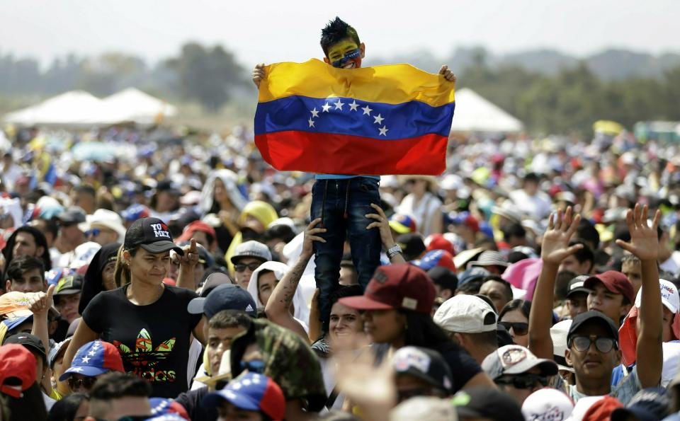 FILE - In this Feb. 22, 2019 file photo, a child holds a Venezuelan flag during the Venezuela Aid Live concert on the Colombian side of Tienditas International Bridge on the outskirts of Cucuta, Colombia, on the border with Venezuela. Defying orders banning him from leaving Venezuela, Juan Guaidó appears at a star-studded aid concert in neighboring Colombia, joining thousands of other Venezuelans in pressuring Nicolas Maduro to allow the delivery of U.S.-backed emergency food and medicine convoys. (AP Photo/Fernando Vergara, File)