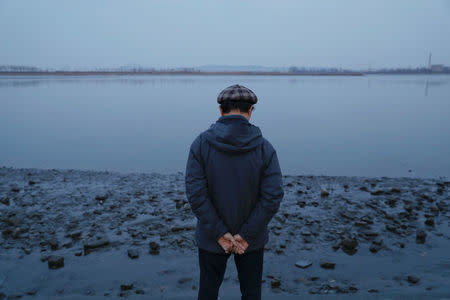 A man pauses at the banks of the Yalu River across from the North Korean town of Sinuiju, in Dandong, China's Liaoning province, March 31, 2017. REUTERS/Damir Sagolj