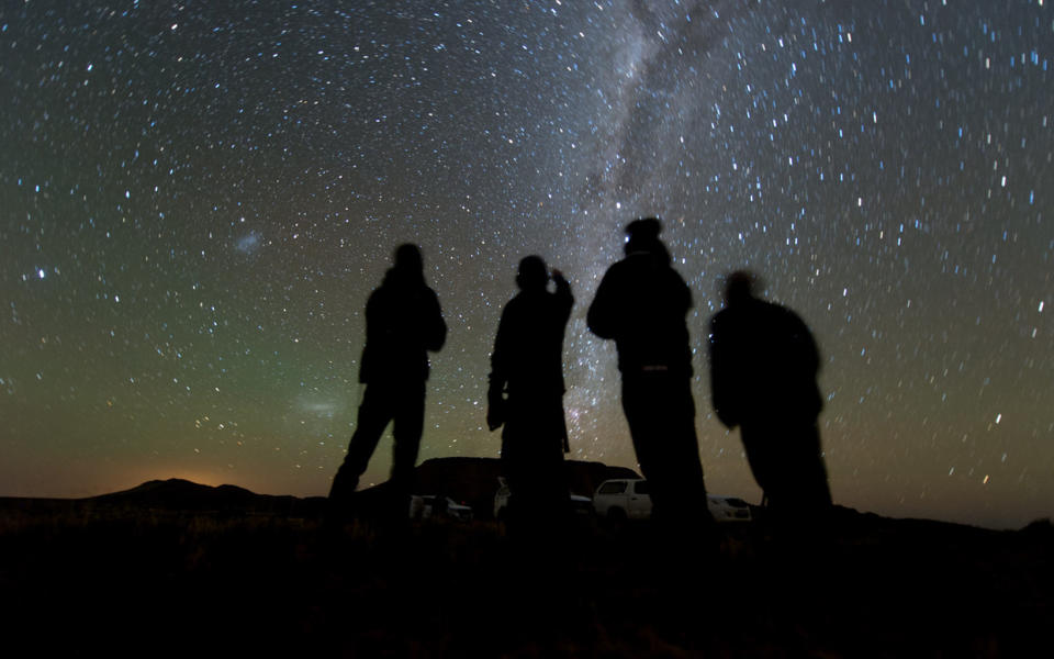 Four members of the South African observation team scan the sky while waiting for the start of the 2014 MU69 occultation, early on the morning of June 3, 2017. They used portable telescopes to observe the event, as MU69, a small Kuiper Belt object and the next flyby target of NASA’s New Horizons spacecraft, passed in front of a distant star. <cite>Henry Throop/NASA/JHUAPL/SwRI</cite>
