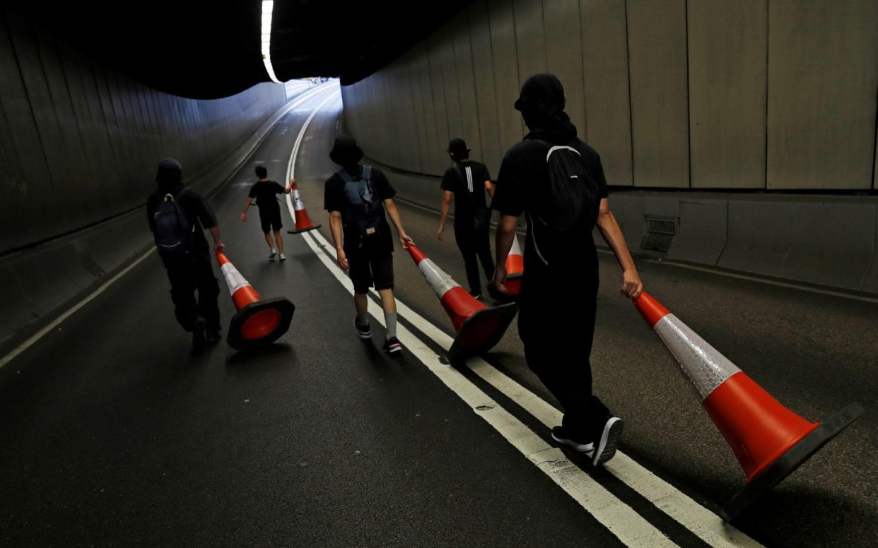 Protesters drag cones to block traffic on a busy road in the centre of the city - REUTERS