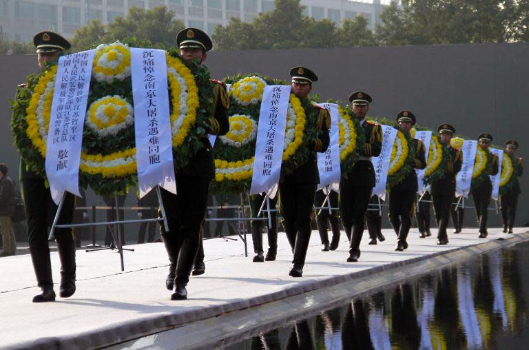 Chinese soldiers carry wreaths as they attend a memorial ceremony for the victims of the Nanjing Massacre, at the Memorial Museum, in Nanjing, on December 13, 2013