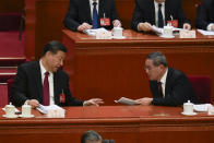 Chinese President Xi Jinping, left, talks with Chinese Premier Li Qiang during the opening session of the National People's Congress (NPC) at the Great Hall of the People in Beijing, China, Tuesday, March 5, 2024. (AP Photo/Ng Han Guan)