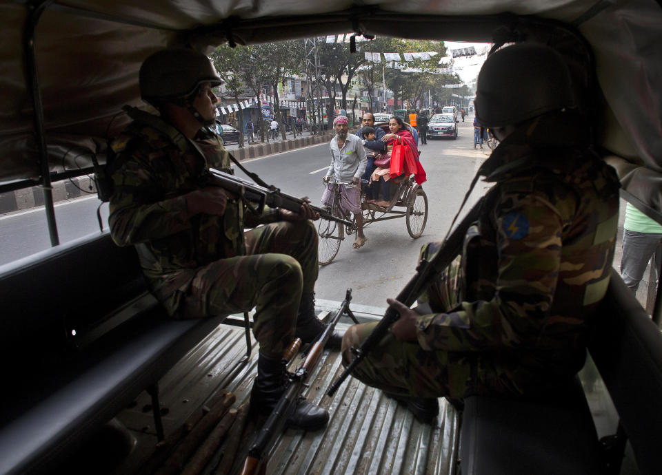 Bangladeshi army soldiers keep vigil as a rickshaw puller transports passengers on the eve of the general elections in Dhaka, Bangladesh, Saturday, Dec. 29, 2018. As Bangladeshis get set for Sunday's parliamentary elections, there are fears that violence and intimidation could keep many away from the polls, including two opposition candidates who said police had barricaded them inside their homes. (AP Photo/Anupam Nath)