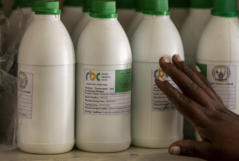 In this photo taken Monday, Nov. 4, 2019, a pharmacist shows bottles of locally-produced oral liquid morphine in the pharmacy of the district hospital in Kibogora, Rwanda. While people in rich countries are dying from overuse of prescription painkillers, people in Rwanda and other poor countries are suffering from a lack of them, but Rwanda has come up with a solution to its pain crisis - it's morphine, which costs just pennies to produce and is delivered to households across the country by public health workers. (AP Photo/Ben Curtis)