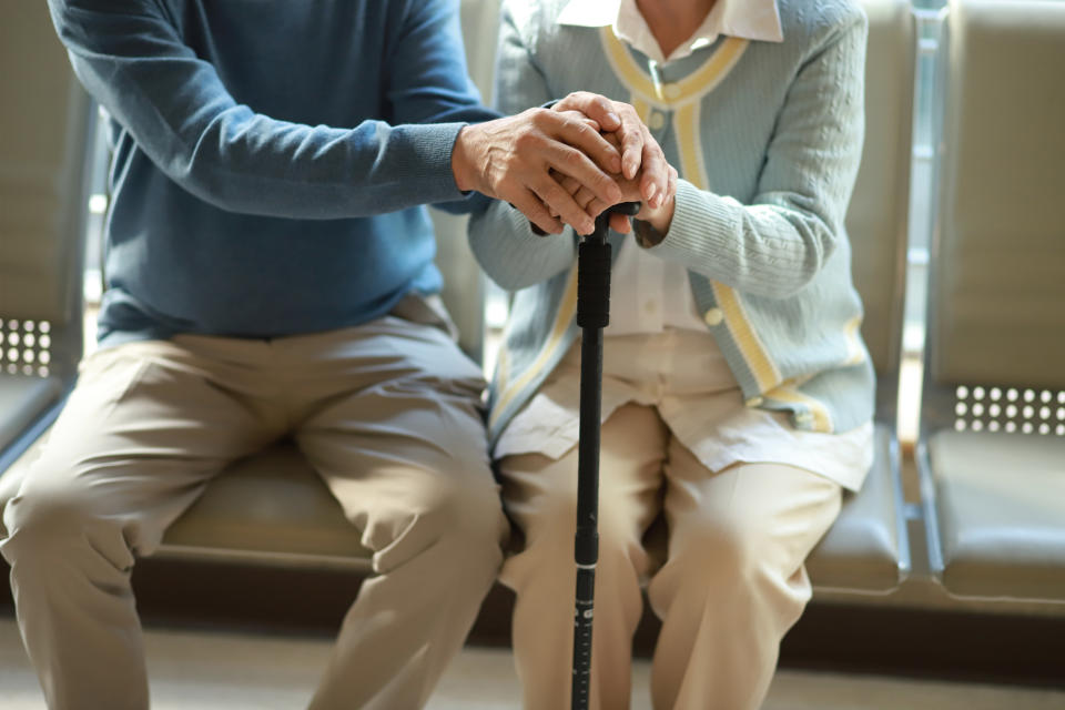 Senior couple holding hands with walking cane