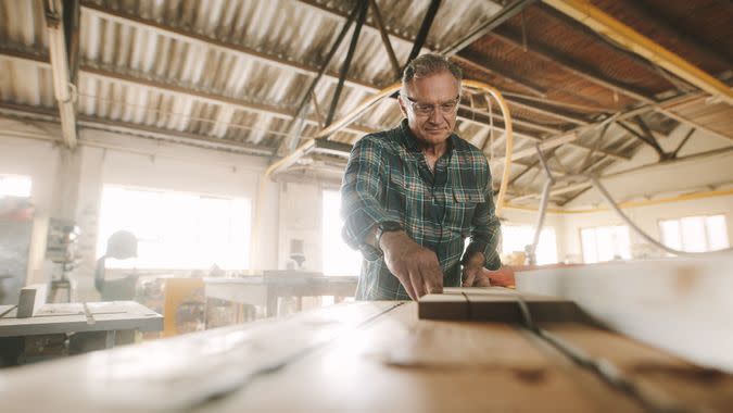 older man in wood shop creating furniture hobby