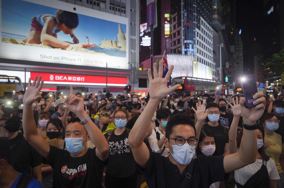 Protesters singing and gesture with five fingers, signifying the "Five demands - not one less" during a protest in Causeway Bay, Hong Kong, Friday, June 12, 2020. Protesters in Hong Kong got its government to withdraw extradition legislation last year, but now they're getting a more dreaded national security law, and the message from Beijing is that protest is futile. (AP Photo/Vincent Yu)