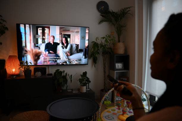 A woman poses as she watches an episode of the newly released Netflix docuseries ‘Harry and Meghan' about Britain’s Prince Harry, Duke of Sussex, and Britain’s Meghan, Duchess of Sussex, in London on 8 December 2022 (AFP via Getty Images)