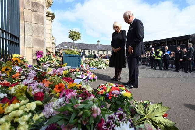 The King Charles and Queen Consort look at floral tributes as they arrive at Hillsborough Castle, Co Down