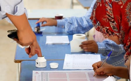 A voter stains her finger with ink at a polling station during a second round runoff of a presidential election in Tunis