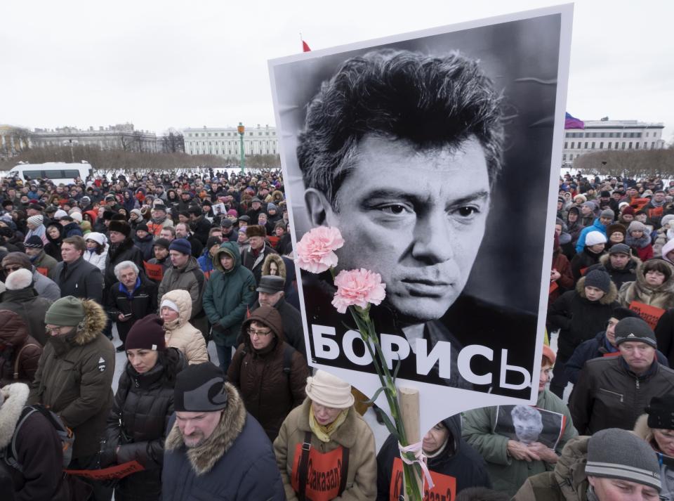 FILE - People gather in memory of opposition leader Boris Nemtsov, portrait in center, in St. Petersburg, Russia, Feb. 26, 2017. Kremlin critics, turncoat spies and investigative journalists have been attacked or killed in a variety of ways. Assassination attempts against foes of President Vladimir Putin have been common during his nearly quarter century in power. Once deputy prime minister under Boris Yeltsin, Boris Nemtsov was a popular politician and harsh critic of Putin. On a cold February night in 2015, he was gunned down by assailants on a bridge adjacent to the Kremlin as he walked with his girlfriend in a death that shocked the country. (AP Photo/Dmitri Lovetsky, file)