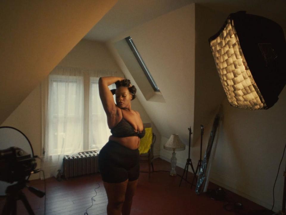 Jasmine Espy in a room in black leggings and a black bra with her arm over her head showing her hidradenitis suppurativa cysts