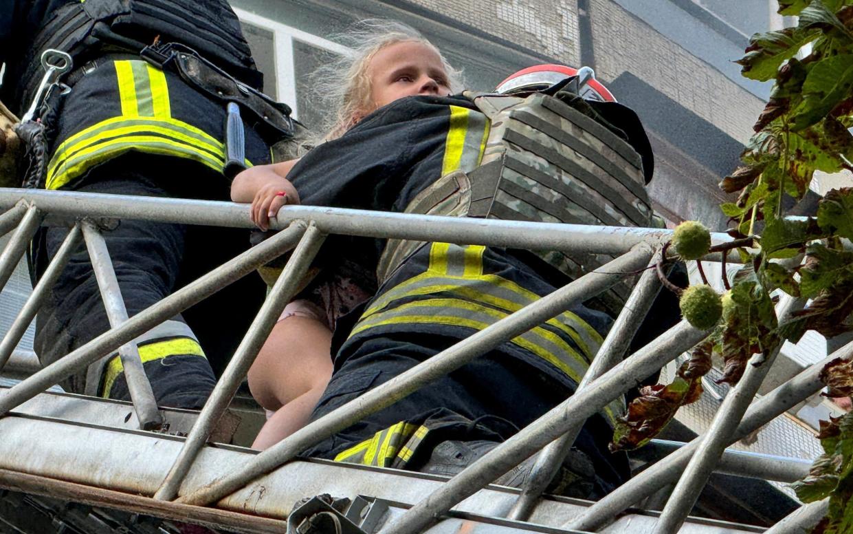 Firefighters carry out a girl out from a residential building hit by a Russian air strike on Kharkiv on Friday