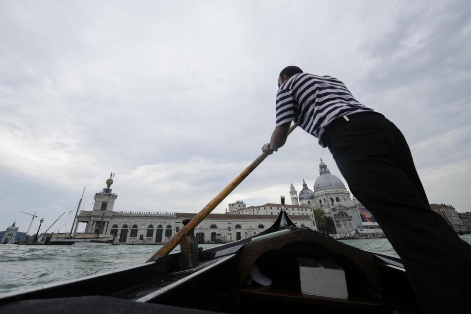 A gondolier rows as he transports tourists for a short canal crossing, in Venice, Italy, Wednesday, Sept. 13, 2023. The Italian city of Venice has been struggling to manage an onslaught of tourists in the budget travel era. The stakes for the fragile lagoon city are high this week as a UNESCO committee decides whether to insert Venice on its list of endangered sites. (AP Photo/Luca Bruno)