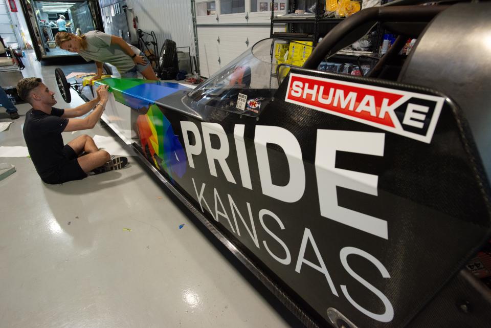 Drag racer Travis Shumake, left, works with team manager and fellow driver Megan Meyer to create a custom geometric rainbow-colored wrap around a race car Tuesday in their Spring Hill shop. Shumake is being sponsored by the Greater Topeka Partnership as the first openly gay drag racer. He will compete at Heartland Park this weekend.