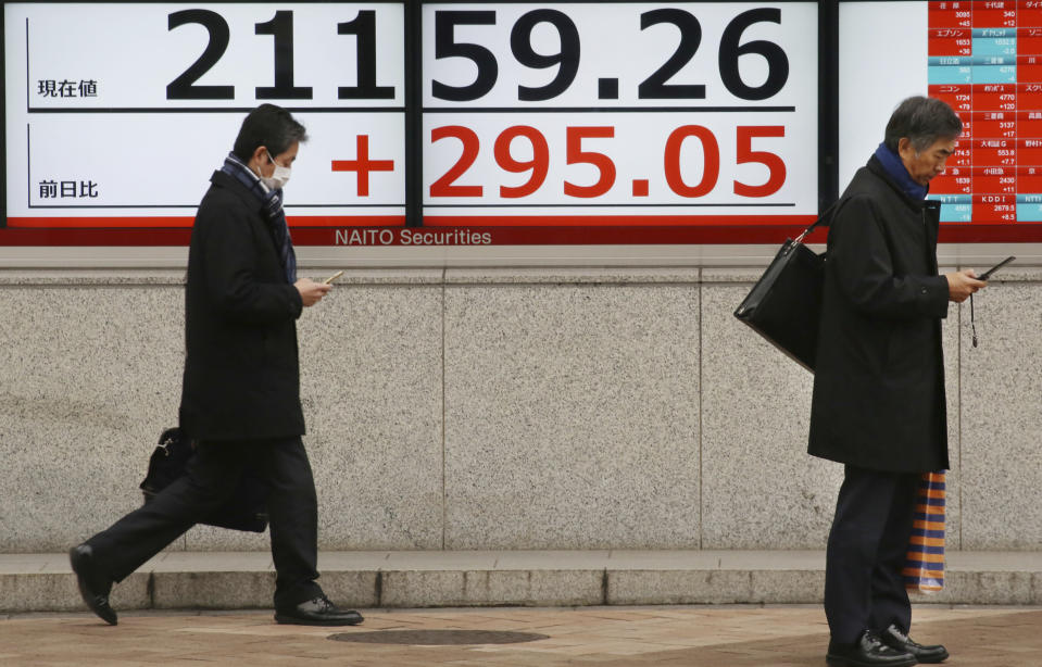 People walk by an electronic stock board of a securities firm in Tokyo, Wednesday, Feb. 13, 2019. Asian shares were mostly higher Wednesday, cheered by prospects for a resolution to the costly trade dispute between the U.S. and China, which had also sent Wall Street indexes higher. (AP Photo/Koji Sasahara)