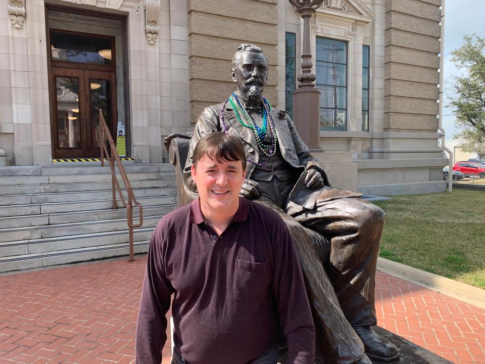 Mike Miller, executive director of the Rosenberg Library in Galveston, stands next to a statue of Henry Rosenberg, a businessman and philanthropist who died in 1893 and endowed the library, museum and history center.