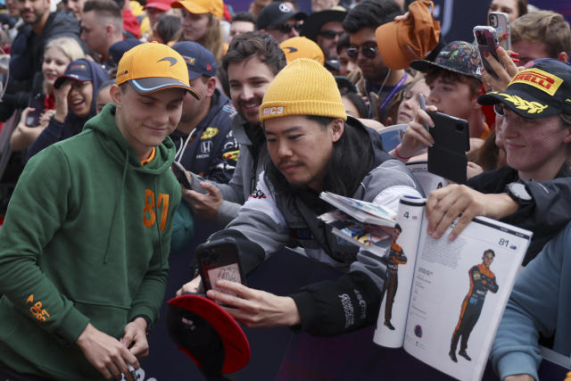 McLaren driver Oscar Piastri of Australia, left, poses for photos with fans as he arrives at the track ahead of the Australian Formula One Grand Prix at Albert Park in Melbourne, Thursday, March 30, 2023. (AP Photo/Asanka Brendon Ratnayake)