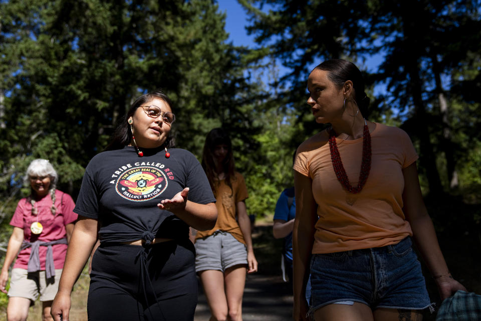 Serina Fast Horse, of Sicangu Lakota & Blackfeet Tribes, left, talks with Jacy Bowles, of Xicana and Diné descent, talk as they walk to the former Elwha Dam site during the 2023 Tribal Climate Camp on the Olympic Peninsula Wednesday, Aug. 16, 2023, near Port Angeles, Wash. Participants representing at least 28 tribes and intertribal organizations gathered to connect and share knowledge as they work to adapt to climate change that disproportionally affects Indigenous communities. More than 70 tribes have taken part in the camps that have been held across the United States since 2016. (AP Photo/Lindsey Wasson)