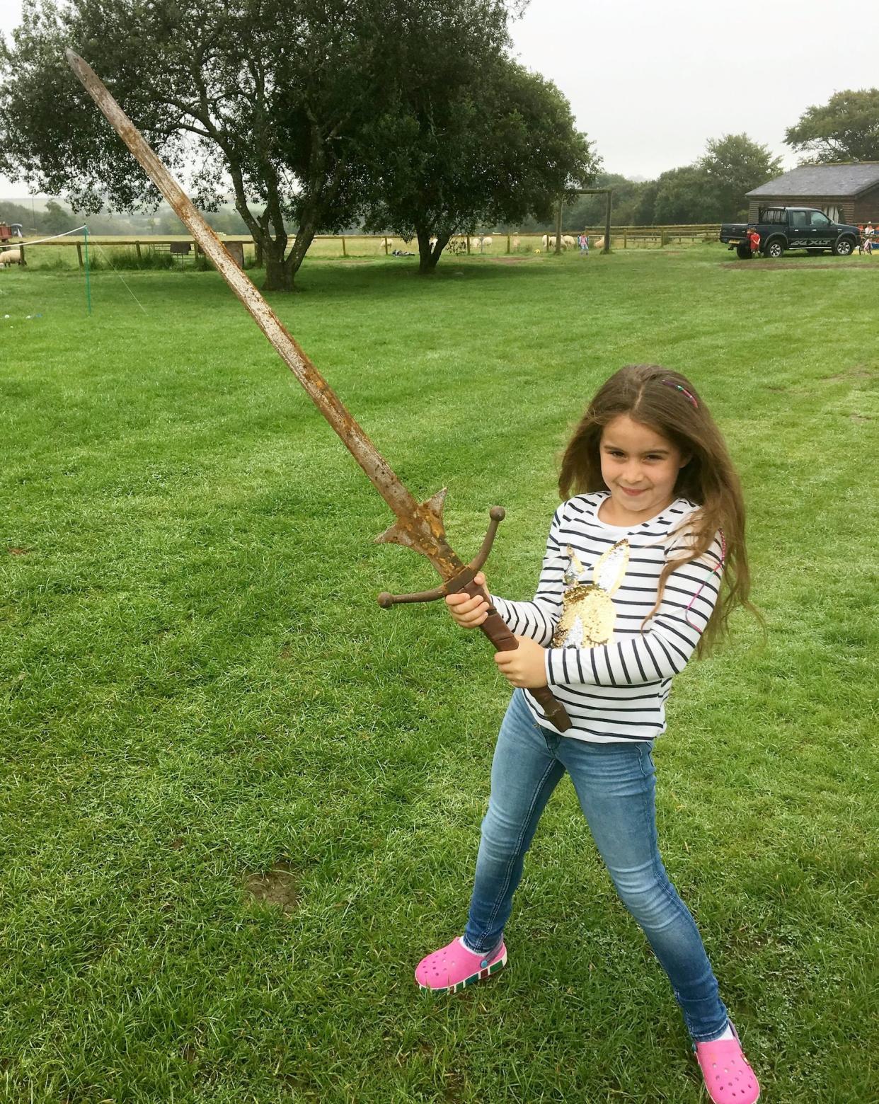 Matilda Jones, from Norton, Doncaster, shows off a mighty sword that she found at the bottom of a lake where King Arthur's said to have returned his Excalibur. (Photo: SWNS)