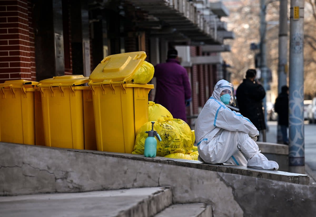 A worker wearing personal protective equipment (PPE) sits next to waste material outside a fever clinic amid the Covid-19 pandemic in Beijing on Monday  (AFP via Getty Images)