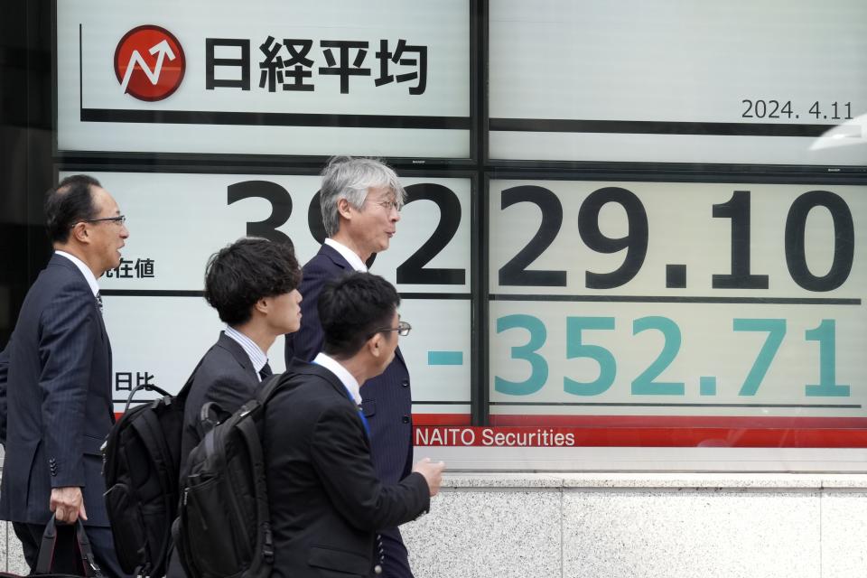 People walk past an electronic stock board showing Japan's stock prices at a securities firm Thursday, April 11, 2024, in Tokyo. (AP Photo/Eugene Hoshiko)