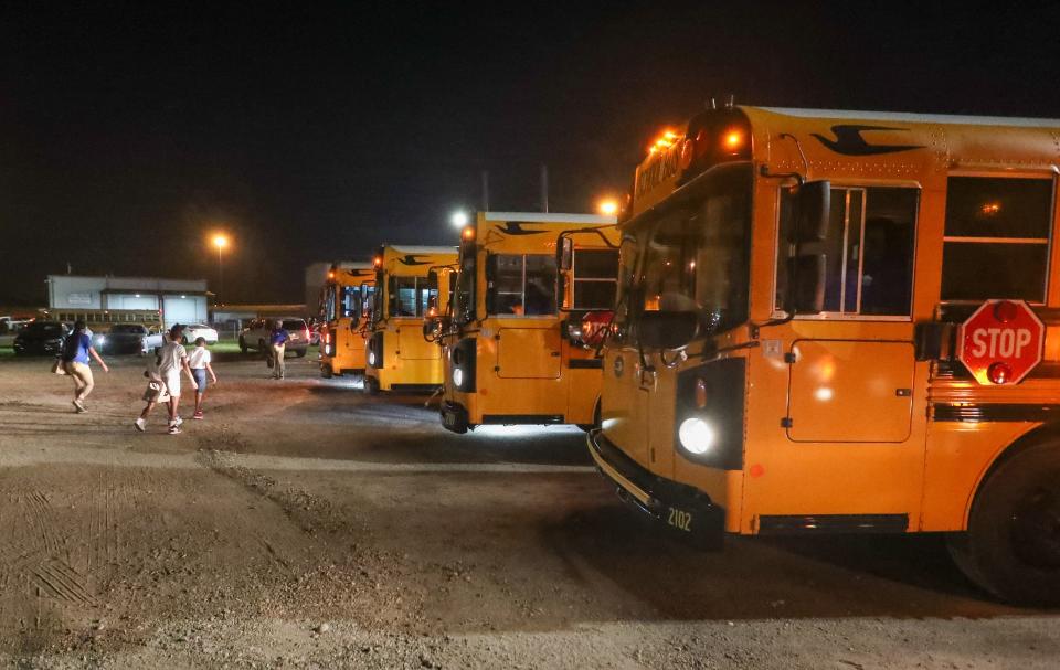 A driver walks with children to a bus at the SCCPSS Transportation Facility as bus drivers prepare to go out for the first day of the 2023-24 school year on Thursday, August 3, 2023.