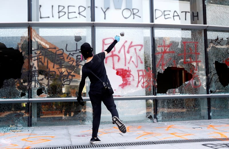 FILE PHOTO: A protester throws a stone into a building at Hong Kong Polytechnic University in Hong Kong,