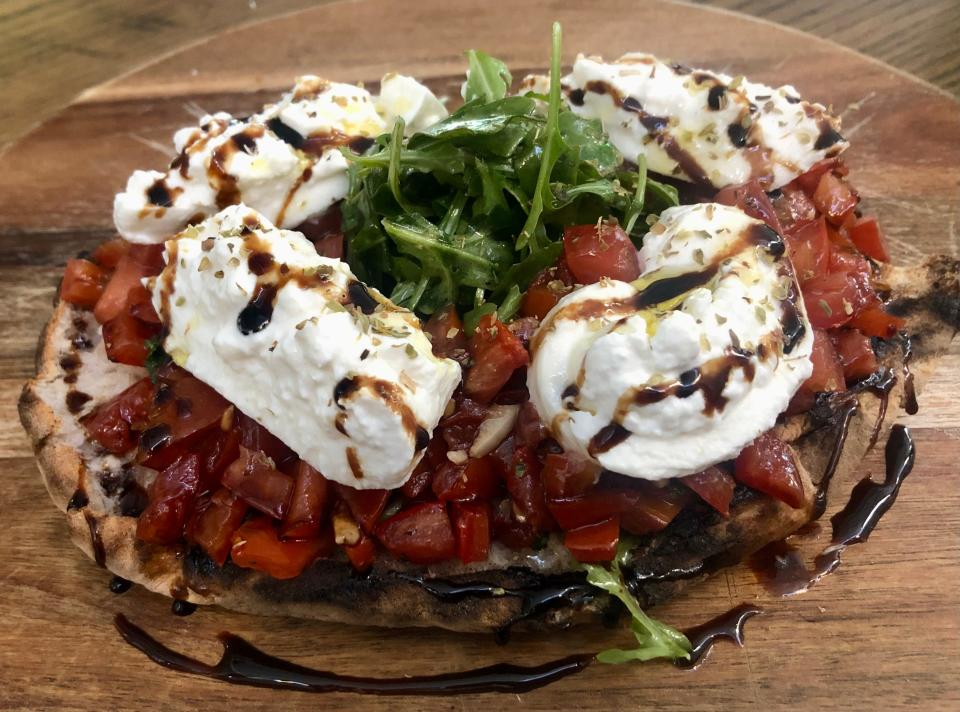 Fresella appetizer is made with wood-fired bread, Roma tomatoes, burrata, extra virgin olive oil, arugula and balsamic.