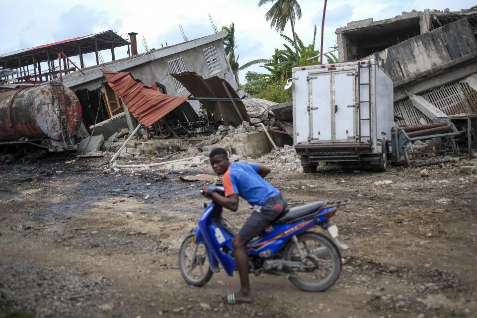 A worker rides his motorbike at the Etheuss vetiver oil factory after it was made inoperable by the 7.2 magnitude earthquake in Les Cayes, Haiti, Thursday, Aug. 19, 2021. Many of the factories that contributed to the multimillion-dollar industry responsible for more than half the world's vetiver oil used in fine perfumes, cosmetics, soaps and aromatherapy, are now inoperable. (AP Photo/Matias Delacroix)