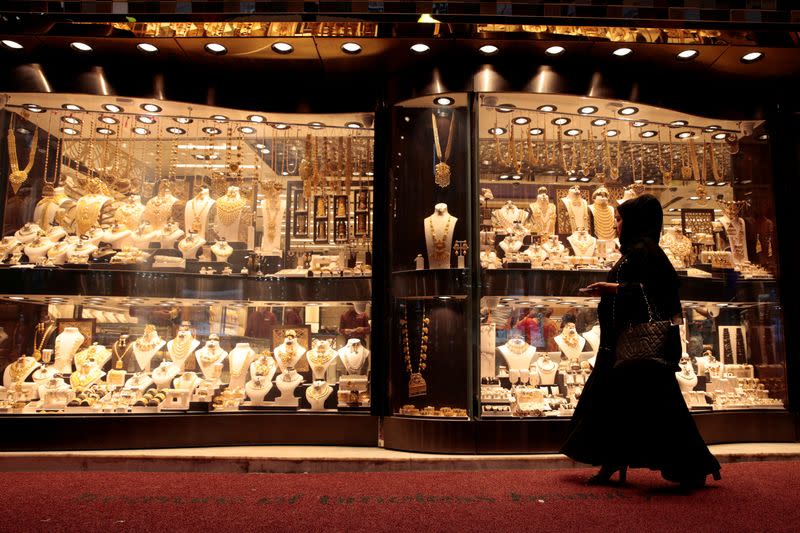 FILE PHOTO: A woman walks past gold jewellery displayed in a shop window at the Gold Souq in Dubai
