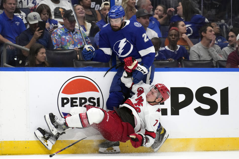 Tampa Bay Lightning left wing Nicholas Paul (20) knocks down Carolina Hurricanes defenseman Dmitry Orlov (7) during the second period of an NHL hockey game Tuesday, Oct. 24, 2023, in Tampa, Fla. (AP Photo/Chris O'Meara)