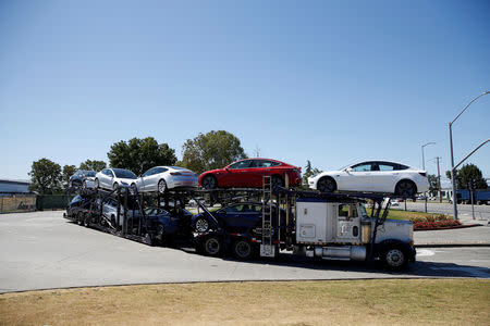 FILE PHOTO: A car carrier trailer carries Tesla Model 3 electric sedans, is seen outside the Tesla factory in Fremont, California, U.S. June 22, 2018. REUTERS/Stephen Lam/File Photo